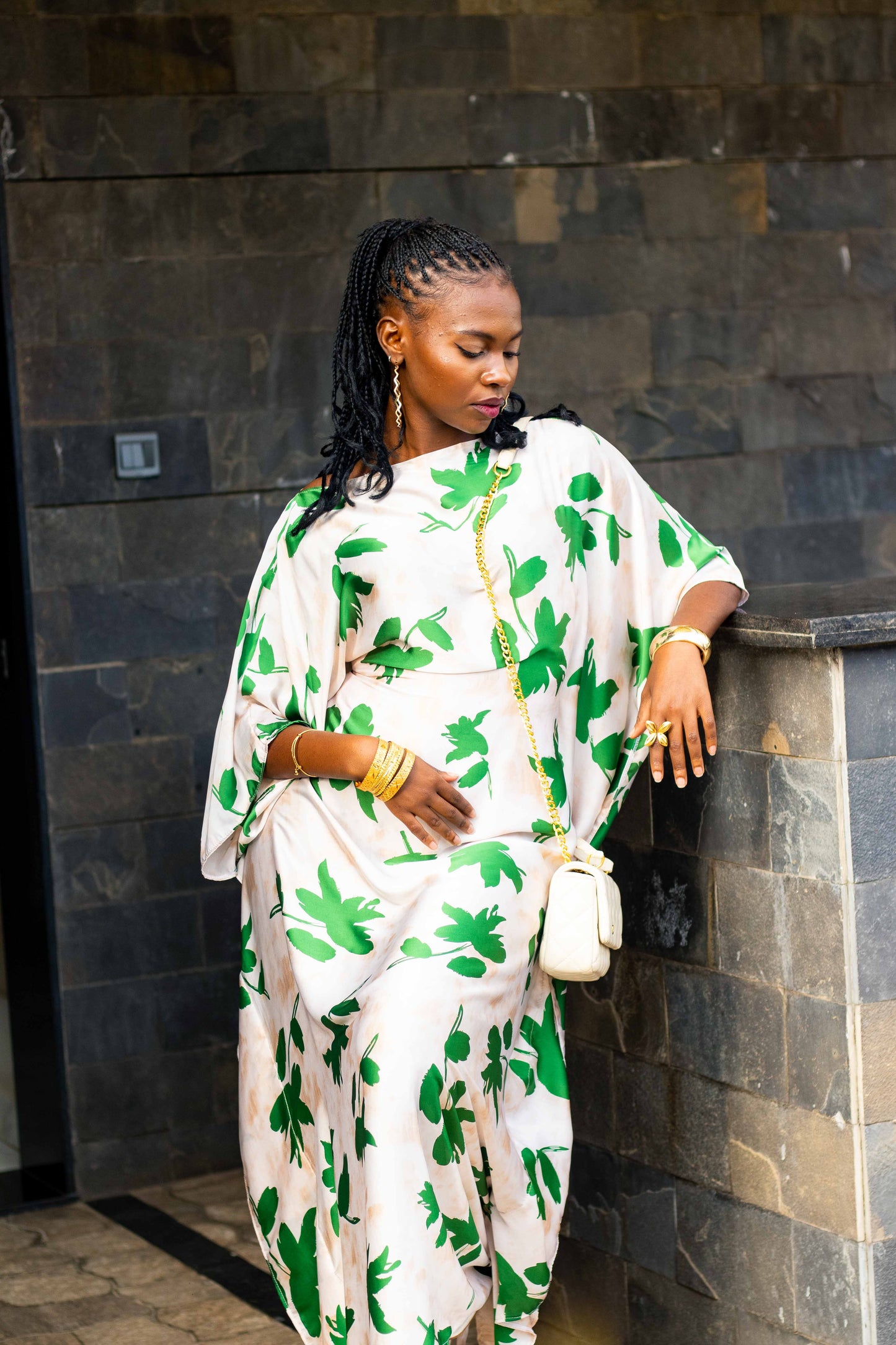 A woman wearing a white kaftan dress with a green palm leaf pattern.