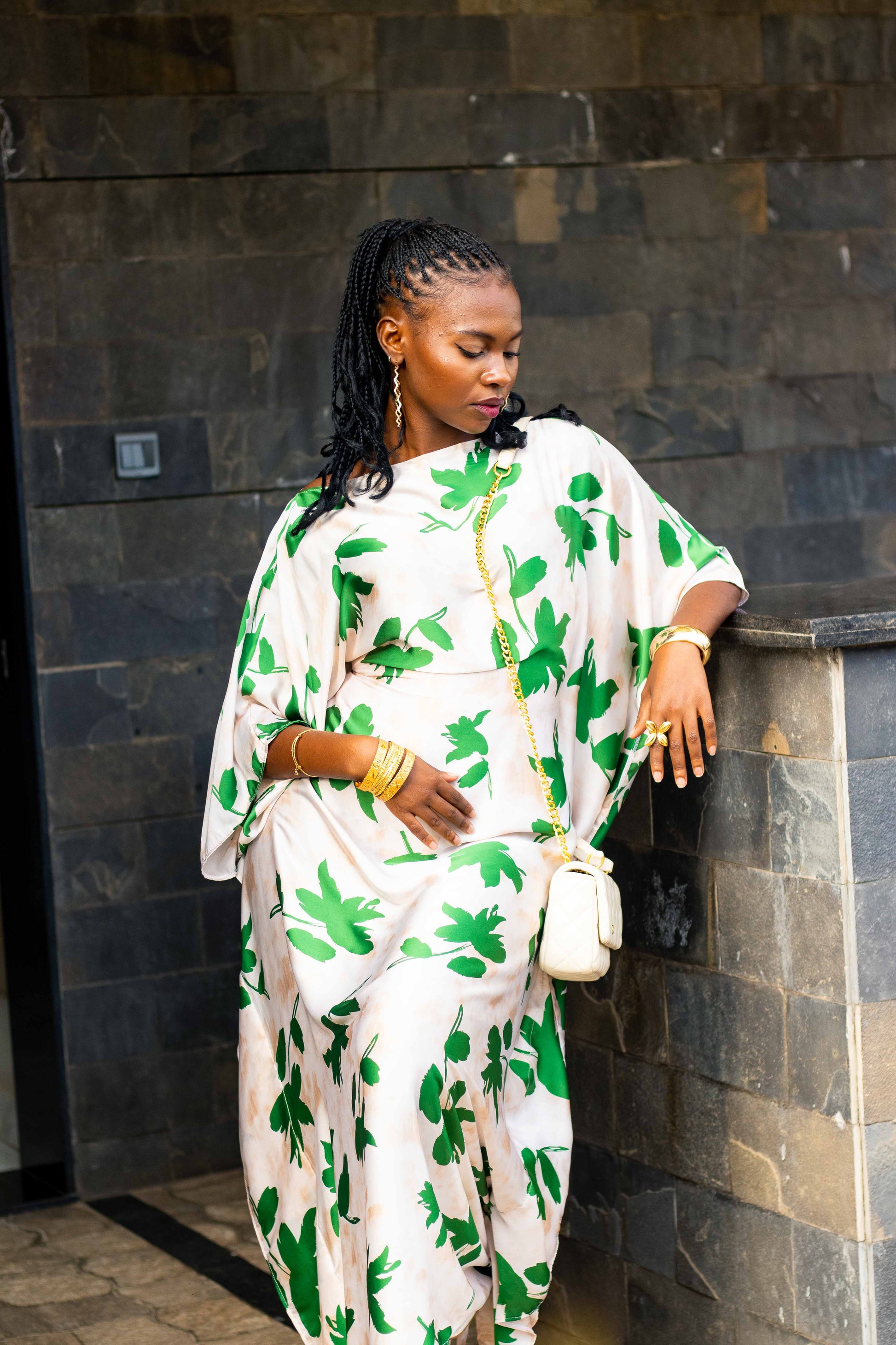 A woman wearing a white kaftan dress with a green palm leaf pattern.